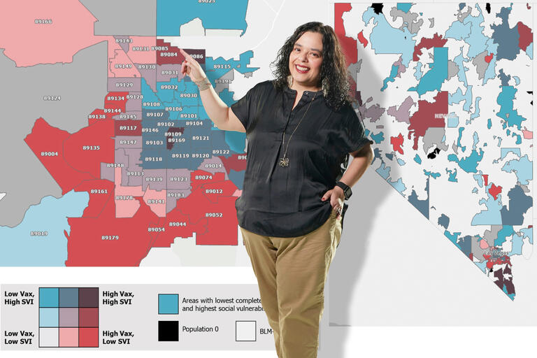 A portrait of Erika Marquez pointing to a wall-sized map of populations in Las Vegas.