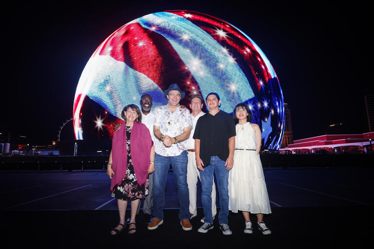group of people stand in front of the Sphere