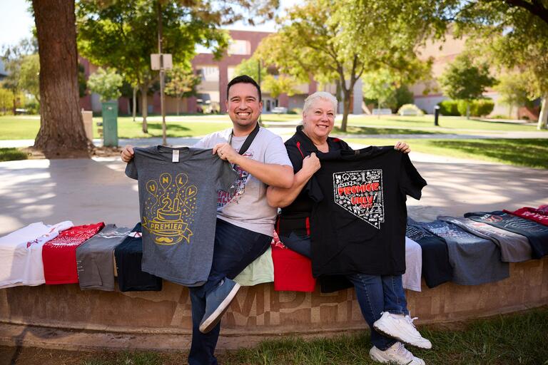 Kevin McVay and Robin Grove holding Premier U.N.L.V. T-shirts