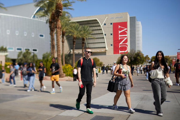 students walking on campus with Lied Library in the background