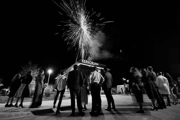 black-and-white photo of group watching fireworks at a building grand opening