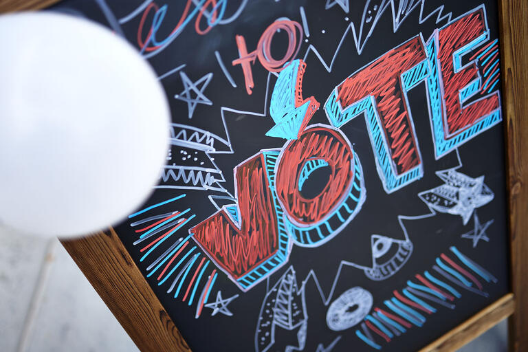 A colorful chalkboard sign with the word &quot;Vote&quot;