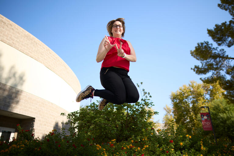 Sonja Rogers jumping in air while using hands to spell 'LV'