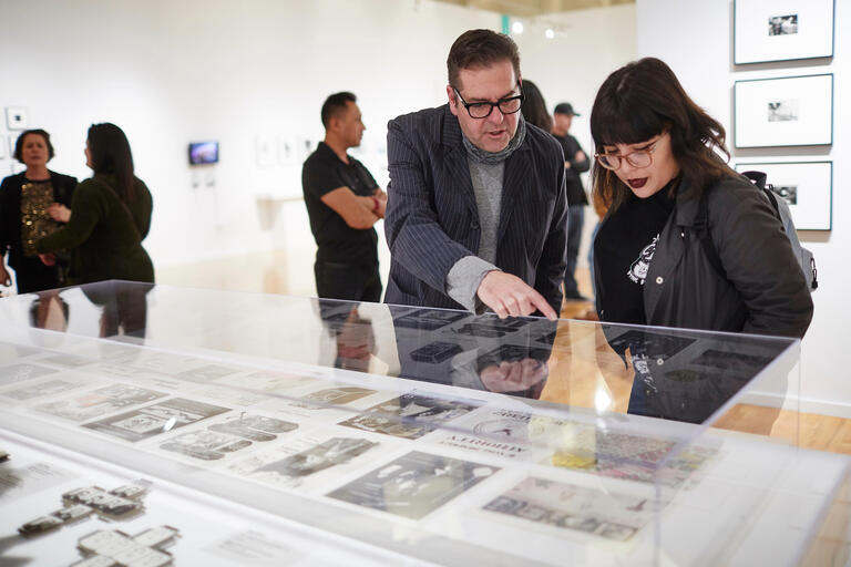 Two people look over an exhibit at the Barrick Art Museum.