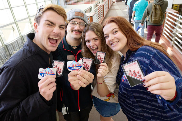 Students pose in Lied Library holding original &quot;I Voted&quot; stickers.