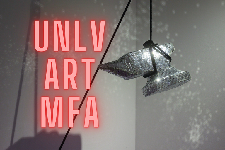 A shiny anvil hanging in an art gallery with the words &quot;UNLV ART MFA&quot;