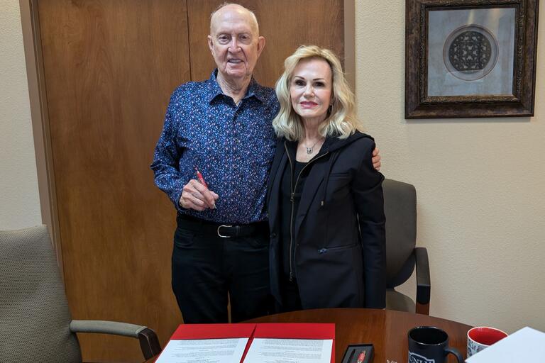 David Mulkey, M.D. and Laura Taylor Mulkey at the gift agreement signing. They can be seen holding a pen and signing documents.