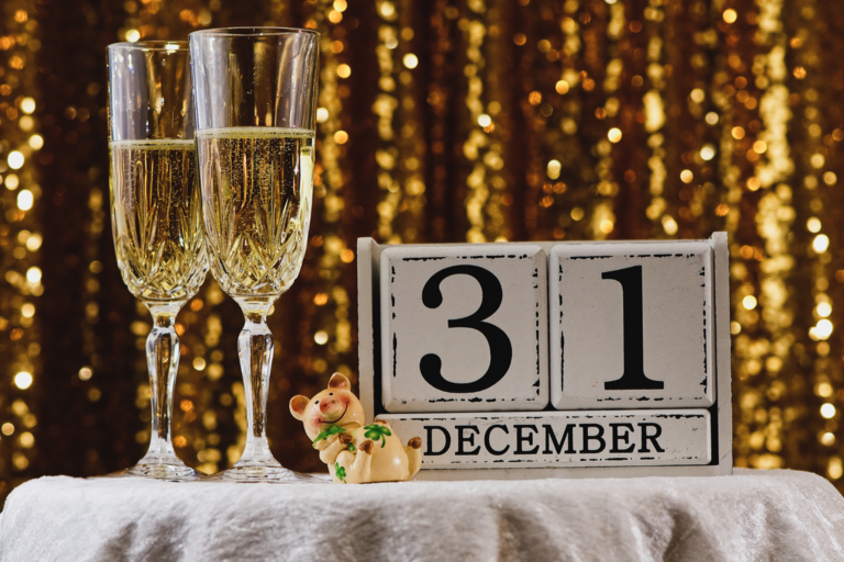 Picture of two half full champagne glasses and white colored date blocks that say thirty-one December