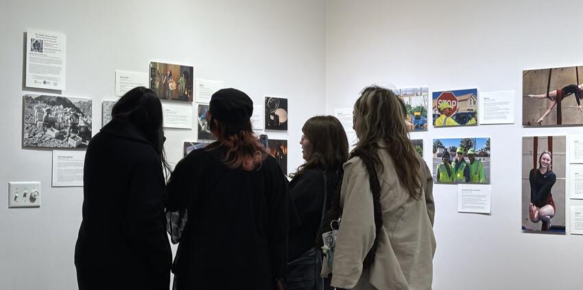 A group of people looking at photographs displayed on an art gallery wall