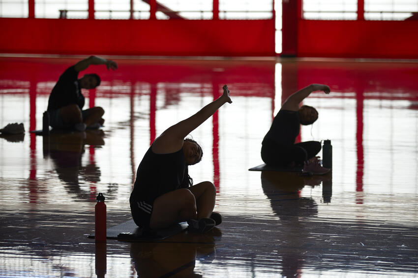 Three students doing yoga stretches.