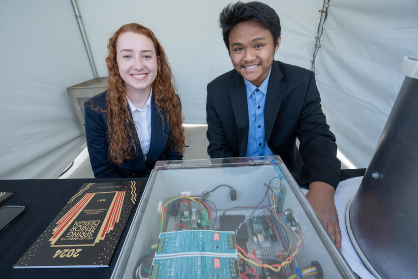 Two students posed in front of their senior design project.