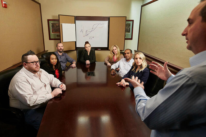 A group of people at a table listening to a man speak