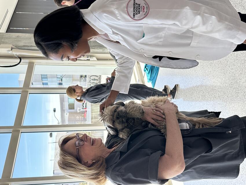 A medical student petting a small dog