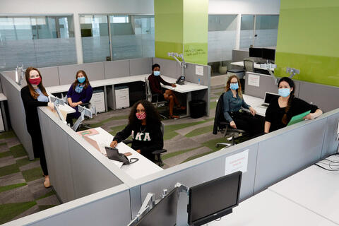 people wearing masks inside a cubicle office
