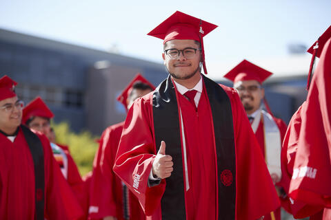 a graduate poses with a thumbs up