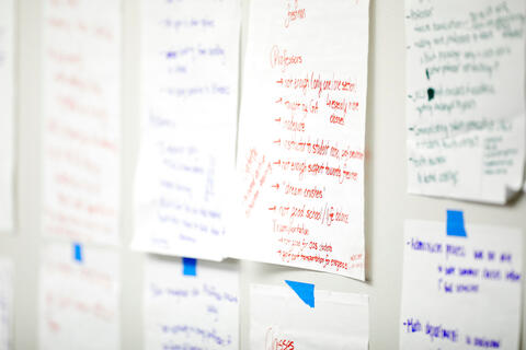 hand written notes posted on a wall with blue tape