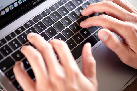 hands typing on a laptop keyboard