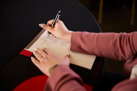 A person writing on a piece of paper with a pen