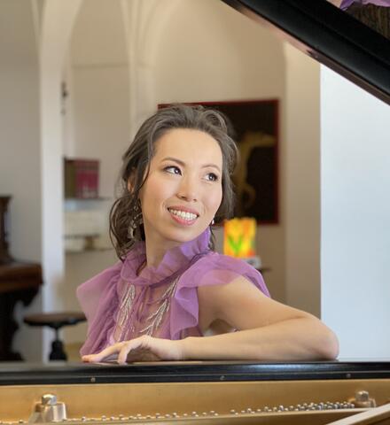 Portrait of Yin Zheng leaning into a piano.